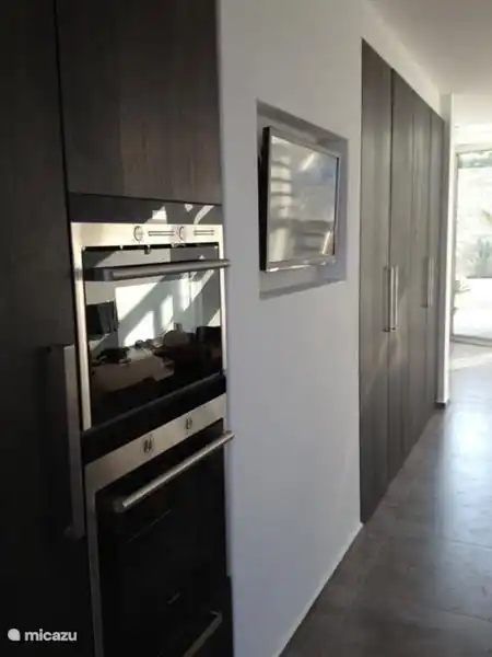 Schrank in der Küche mit Mikrowelle, Backofen, Grill und großem Kühlschrank. Farbe Fernseher funktionierte entfernt in der Wand.