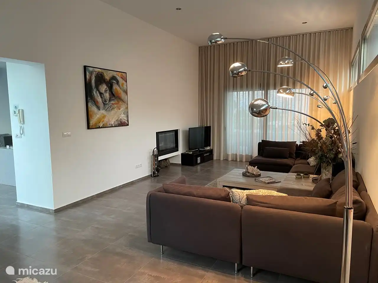 Wohnzimmer mit TV (niederländische Sender), Kamin und Schiebetüren zum Garten mit Swimmingpool.