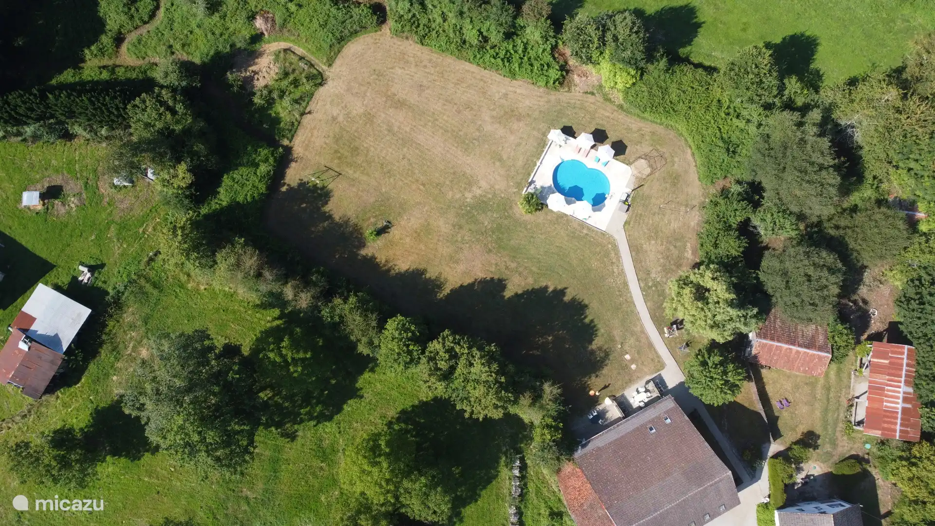 Bovenaanzicht met het zwembad, het omliggende grasveld en de bergen