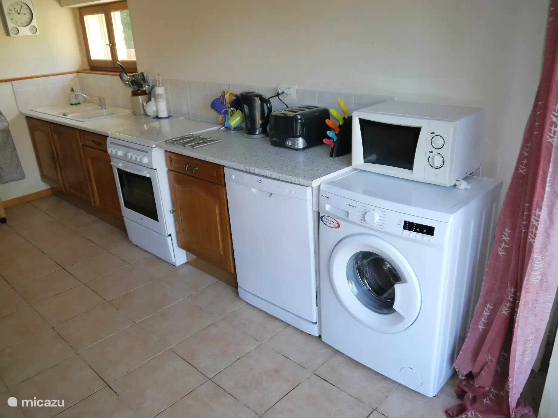 Keuken met gasfornuis, vaatwasser, wasmachine, magnetron, enzovoort