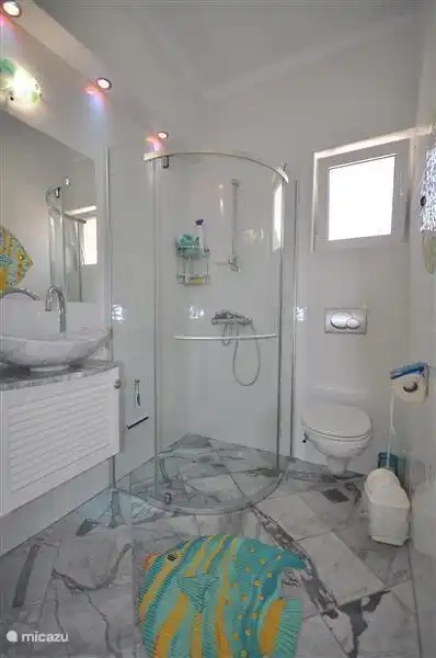 Badezimmer Veronica, Waschbecken, Dusche und WC. Das Mosaik im Bad ist eine Darstellung eines schönen Sonnenbarsche in warmen Tönen.