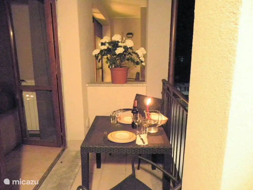 El balcón le invita por la noche a una deliciosa cena con una buena copa de vino.