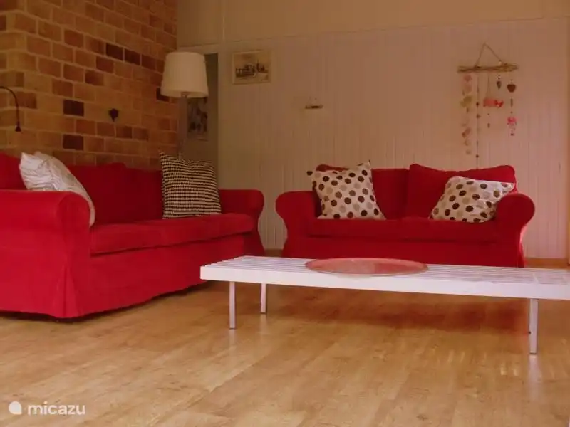 Ruime zithoek met openhaard. Met driezitsbank, een tweezitsbank en stoelen