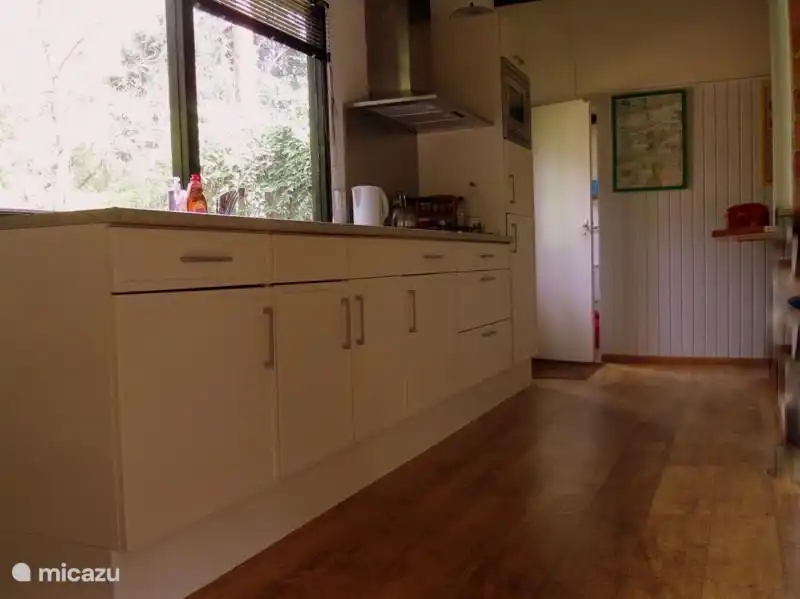 Open keuken, volledig ingericht met uitzicht op de tuin.