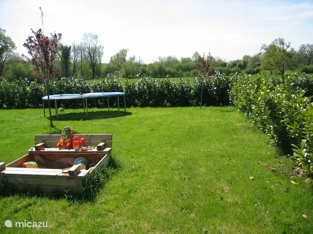 Jardin avec trampoline et bac à sable