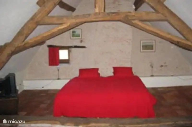 Chambre spacieuse au premier étage avec poutres authentiques et tomettes (carreaux rouges français) au sol.