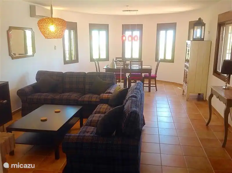 Im hinteren Teil des Wohnzimmers ist ein ausziehbarer Esstisch mit Stühlen.