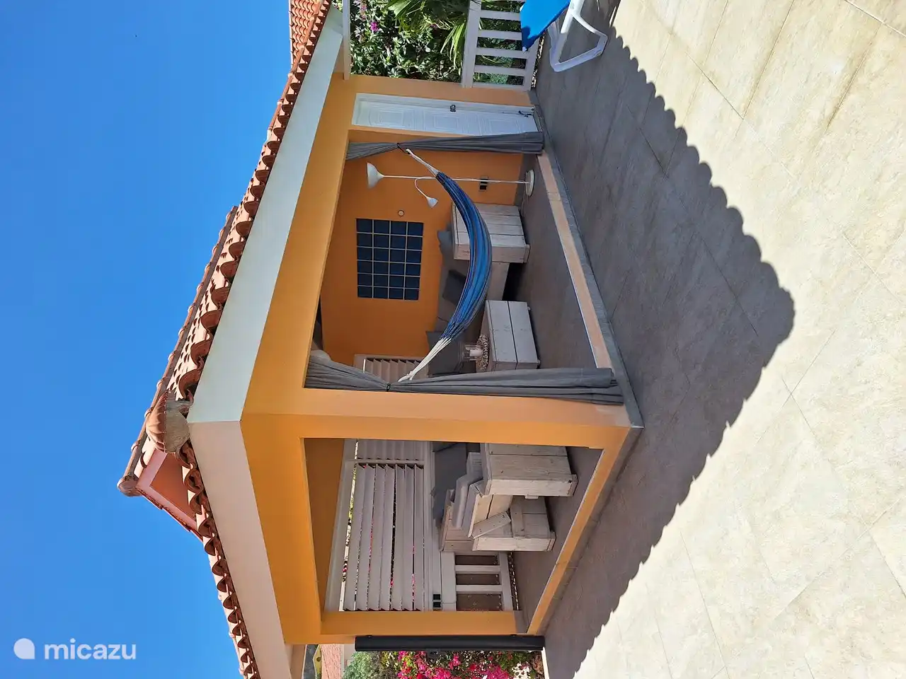 Außenveranda, die mit beweglichen Fensterläden und einem bequemen Lounge-Set ausgestattet ist.