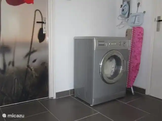 casa vacacional en Surinam, Wanica, Dirección – A la vuelta de la esquina El rincón de lavandería con plancha, tabla de planchar y lavadora.