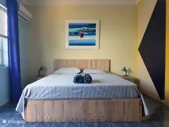 Studio Caribbean Breeze avec un lit queen size en bois de palette robuste.