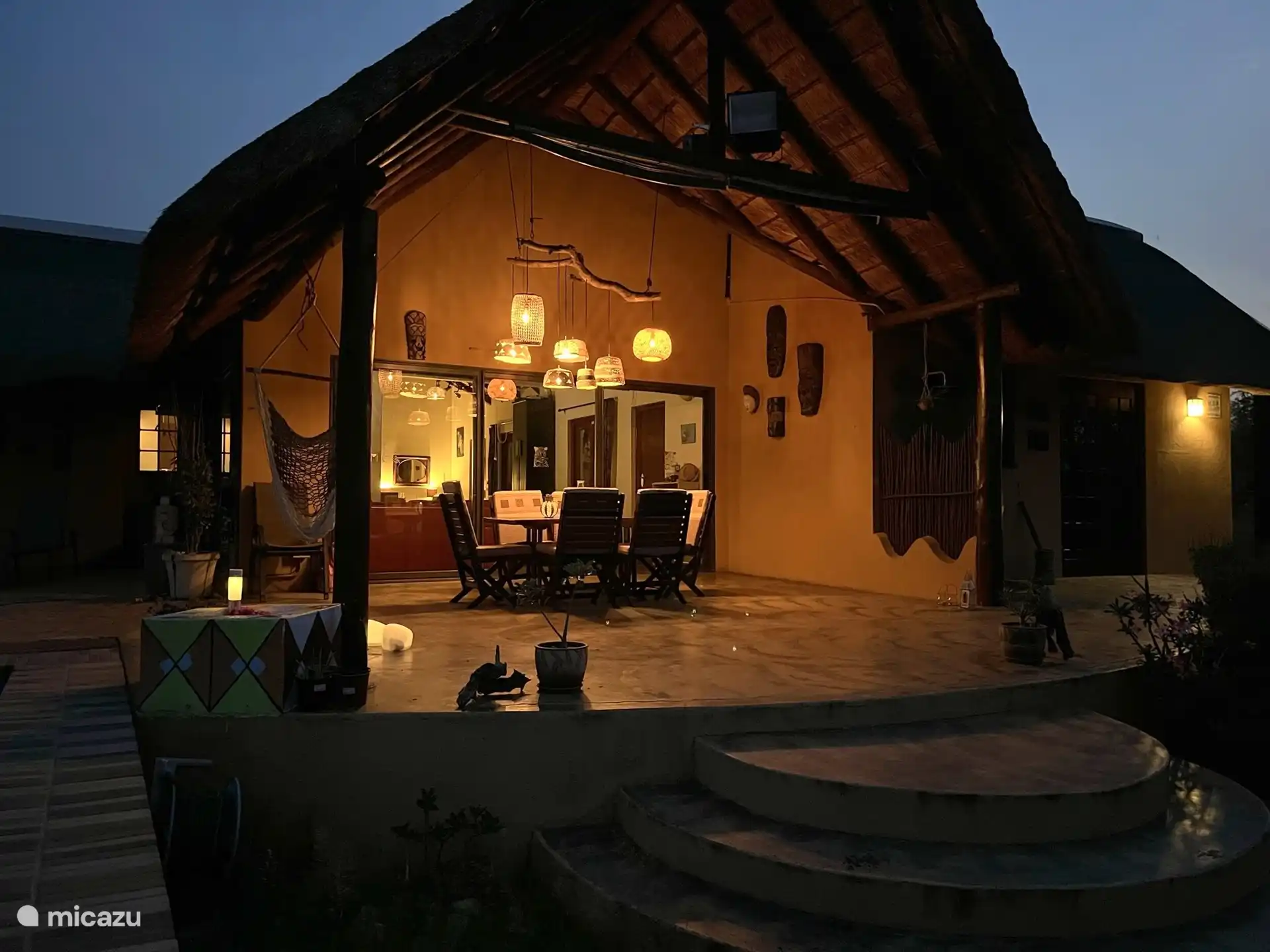 Die Hauptterrasse mit Esstisch und Blick auf das Wasserloch im Garten und den großen Damm, wo die Tiere oft zum Trinken herkommen. 