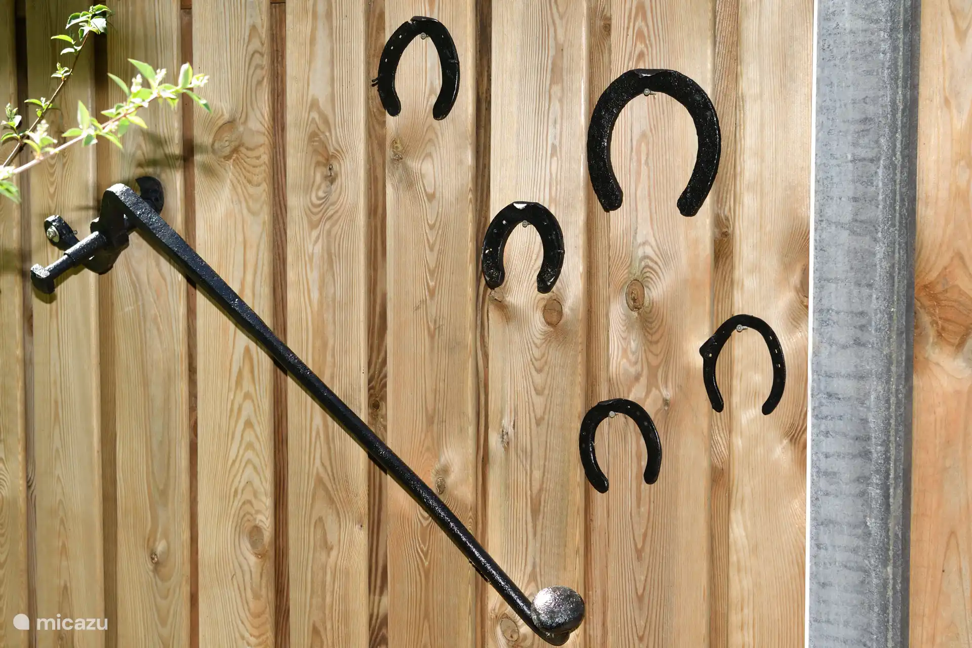Op de schutting zijn nog rudimenten te vinden van de oude boerderij. Links een gehang om een oude pomp te bedienen. Verder nog enkele hoefijzers die verwijzen naar de handel in paarden.