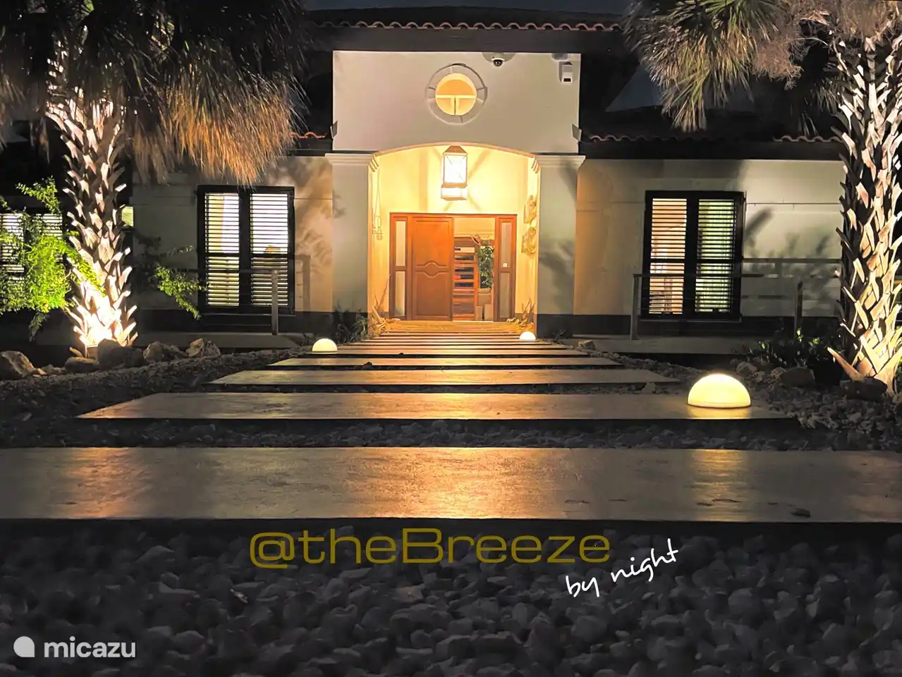 La entrada de Villa @ the Breeze con un jardín iluminado.