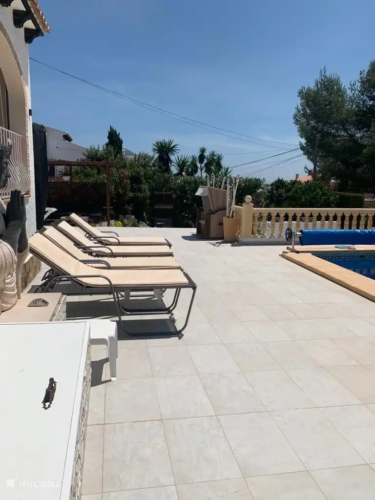 Notre grande terrasse avec transats au bord de la piscine dispose également d'un grand parasol 