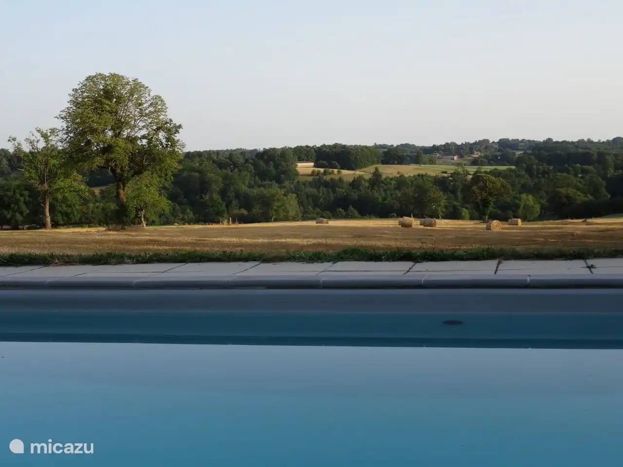 das Schwimmbad und dahinter die Landschaft mit Heuballen 