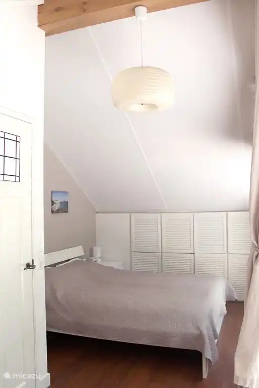 Schlafzimmer mit bequemem Doppelbett, TV und Blick auf den Wald.