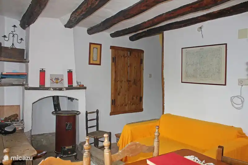 Le salon avec canapé, coin repas et à côté du poêle à bois il y a des radiateurs électriques.