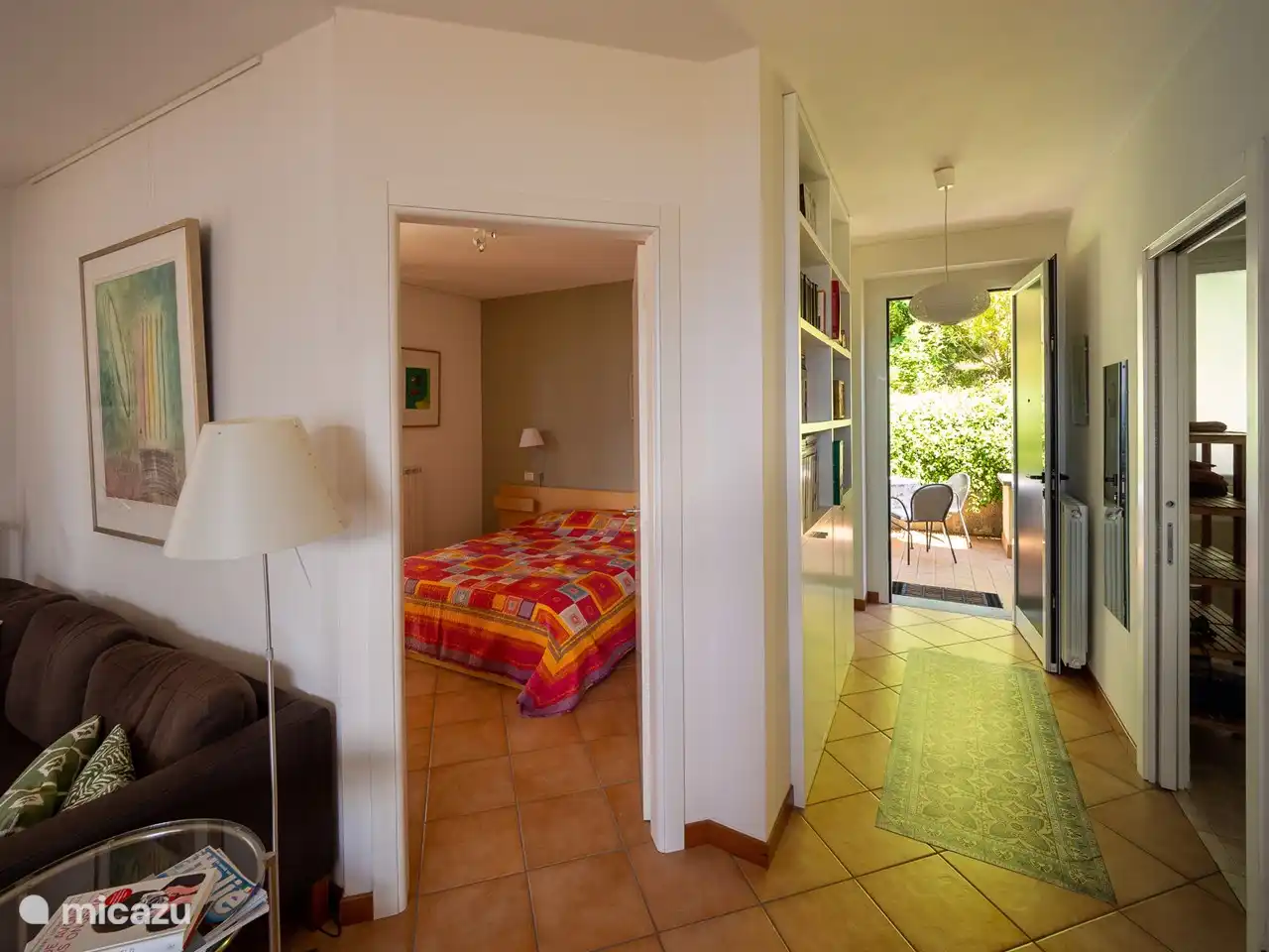 Blick vom Wohnzimmer auf das Schlafzimmer, den Flur mit Bücherregal mit vielen Büchern, Zeitschriften, Touristeninformationen und die Eingangstür zur hinteren Terrasse