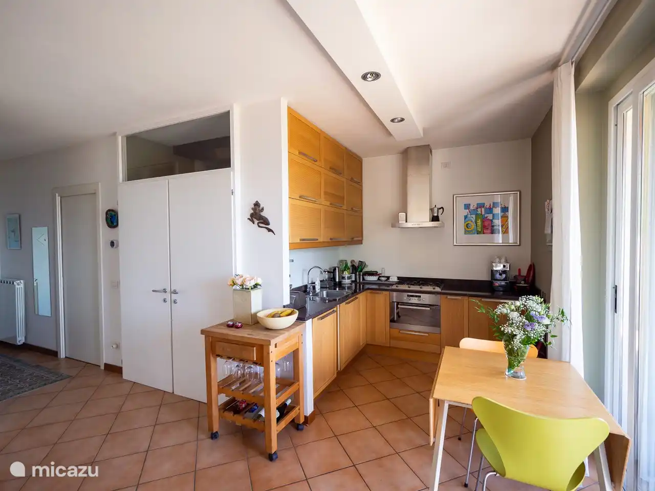 Blick in die Küche, den Essbereich mit Blick auf den See (erweiterbar auf 4 Personen) und den Zugang zum Obergeschoss
