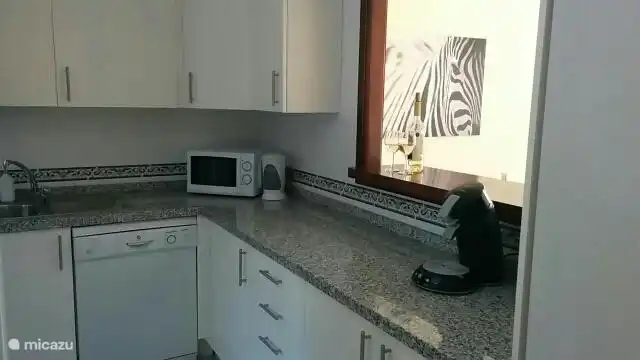 Küche mit Backofen, Ceranfeld, Geschirrspüler, Kühlschrank, Waschmaschine und Trockner.