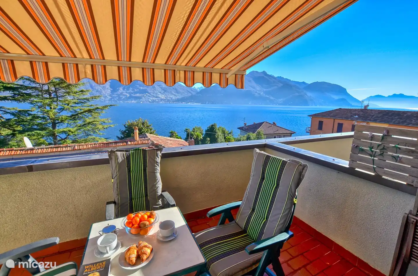 Vista lateral derecha. El amplio balcón con hermosa vista al lago, muebles de exterior y toldo eléctrico. Maravillosa estancia aquí.