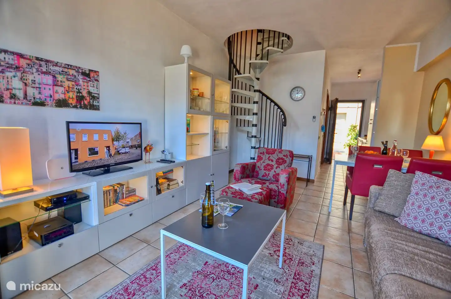 La sala de estar, el comedor, la escalera de caracol al piso superior y la entrada al fondo.