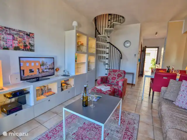 appartement huren in Italië, Comomeer, Acquaseria – Cipresso 33 De woonkamer, eethoek, wenteltrap naar de bovenverdieping en de ingang op de achtergrond.