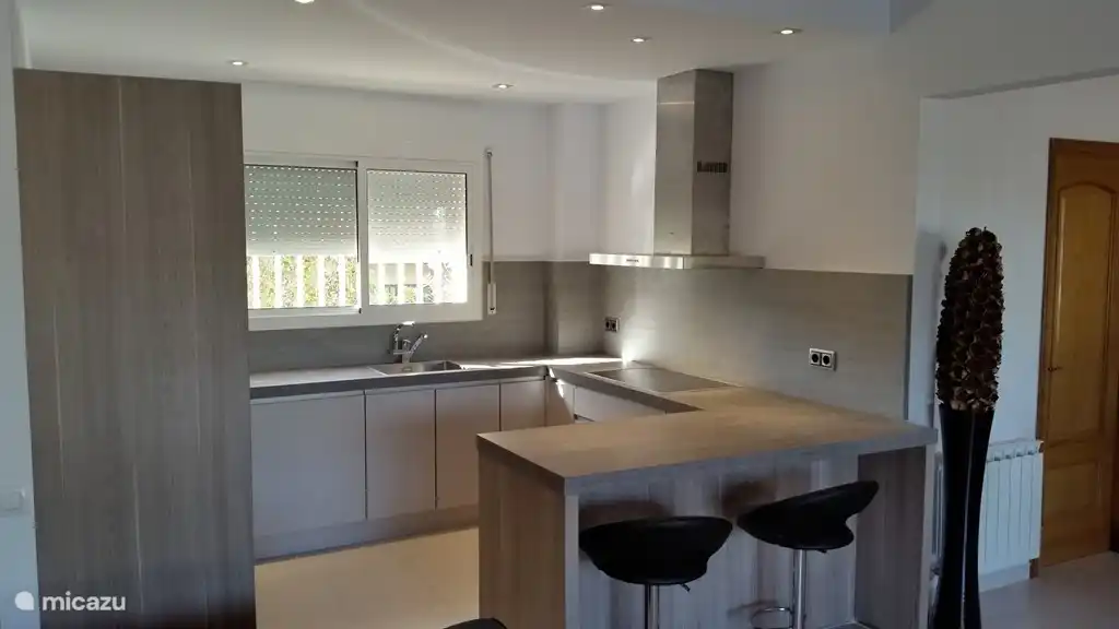 Vollständige moderne Küche mit Geschirrspüler, Induktionskochfeld, Backofen, Mikrowelle, großer Kühlschrank mit Gefrierfach. Waschmaschine und Trockner stehen in einem separaten Raum.