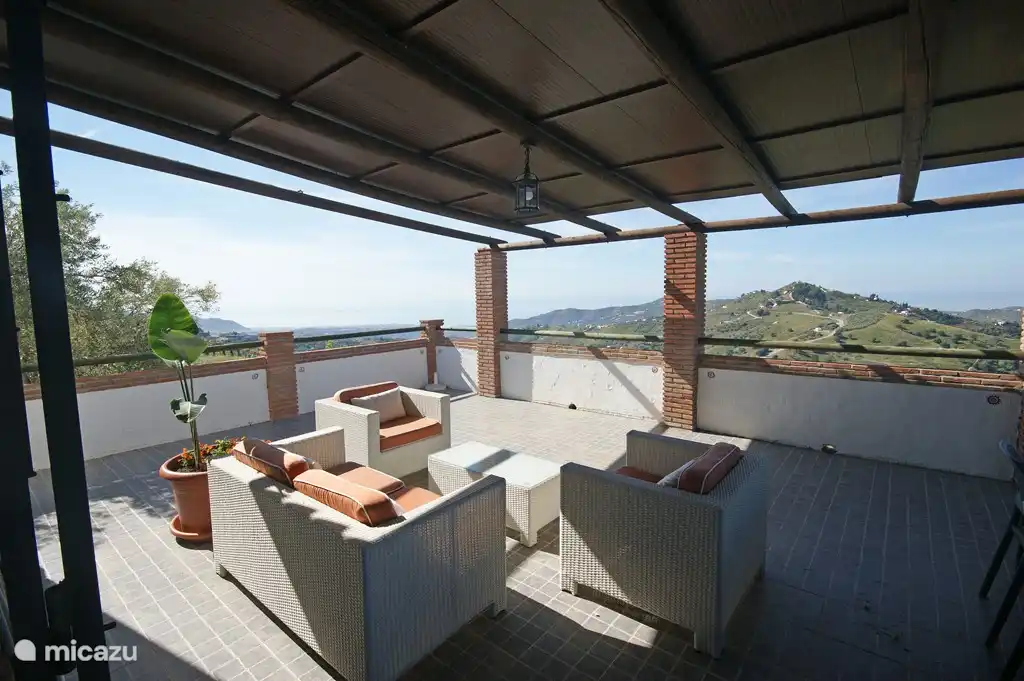 Una hermosa terraza cubierta adyacente a la sala de estar con hermosas vistas.