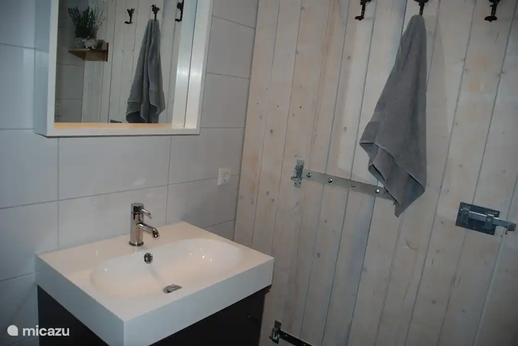 Comfortabele badkamer met vloerverwarming, handdoekradiator, badkamermeubel en douche.