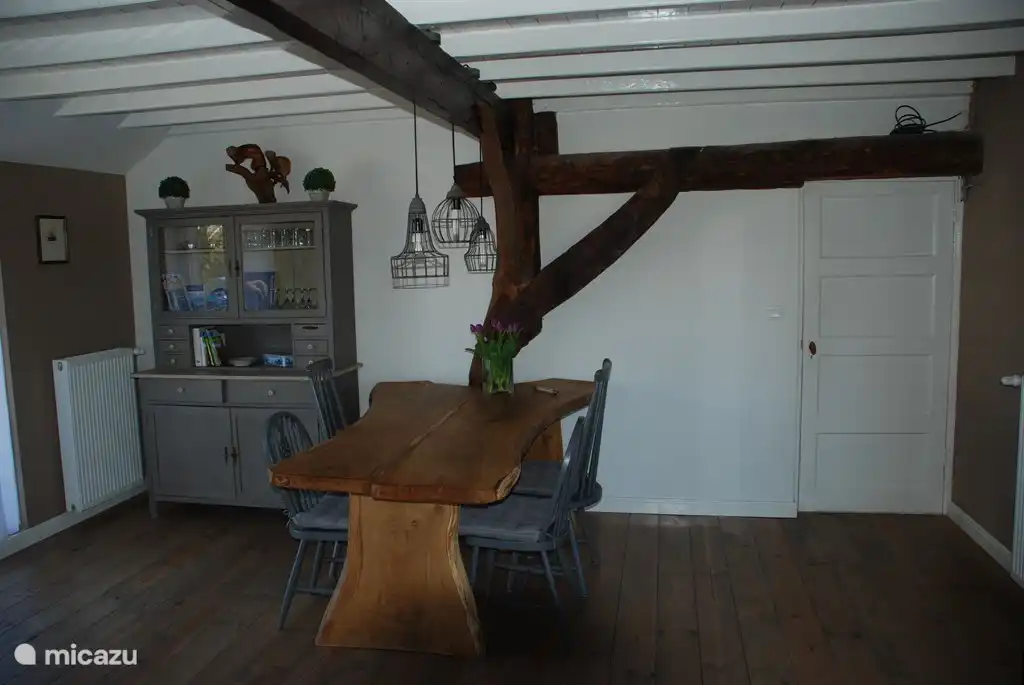 Woonkamer met stoere eiken boomstamtafel en prachtig gebint.