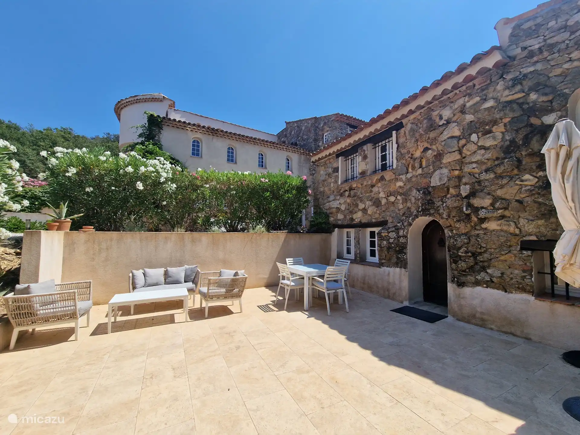 Amplia terraza con salón, mesa de comedor y sombrilla 