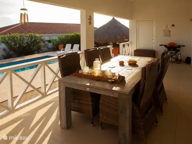 Casa Kontentu en Curazao, Bandabou (oeste), Fontein - casa vacacional El amplio porche con vistas al jardín. Por la mañana se puede escuchar el canto de los pájaros aquí. El juego de comedor se compone de una mesa de teca de 240x100 con 6 sillones de mimbre infinitamente ajustables. También puedes hacer una buena barbacoa en el Porche con la barbacoa de gas Weber