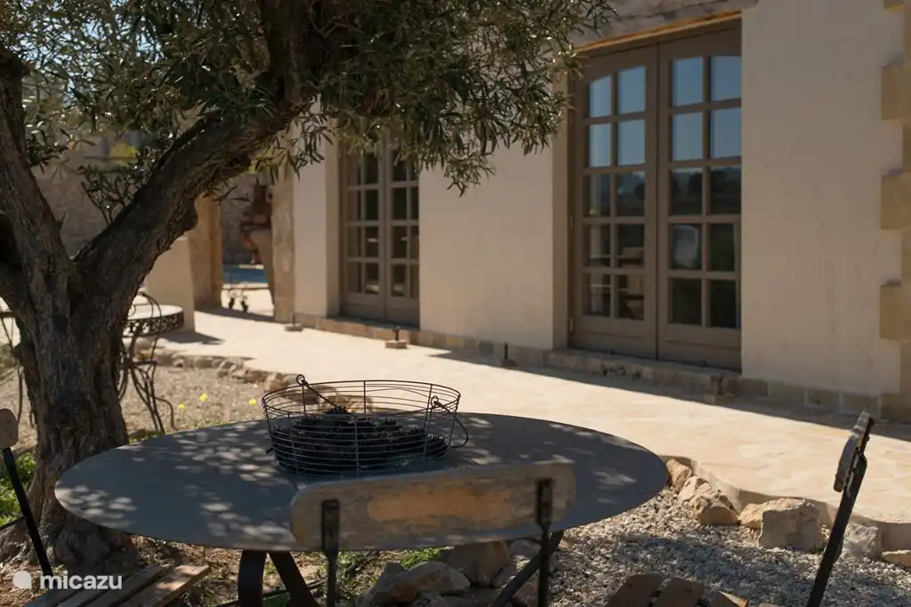 Siéntese bajo el olivo junto a las puertas del patio de los dormitorios en la planta baja.