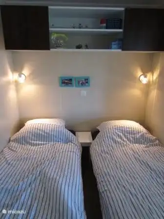 Dormitorio tres con dos camas individuales (80 cm de ancho). (también se pueden juntar para una cama doble).
En la esquina, un armario con espacio para colgar / colocar, encima de las camas, un armario.
Una persiana enrollable para la ventana para mantener alejados a los bichos.