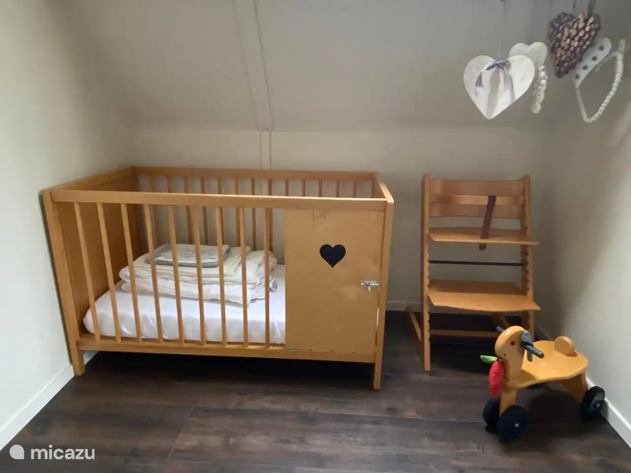 Hay una cuna, una trona y vajilla para niños. Y en la parte superior de las escaleras hay una puerta de escalera. 