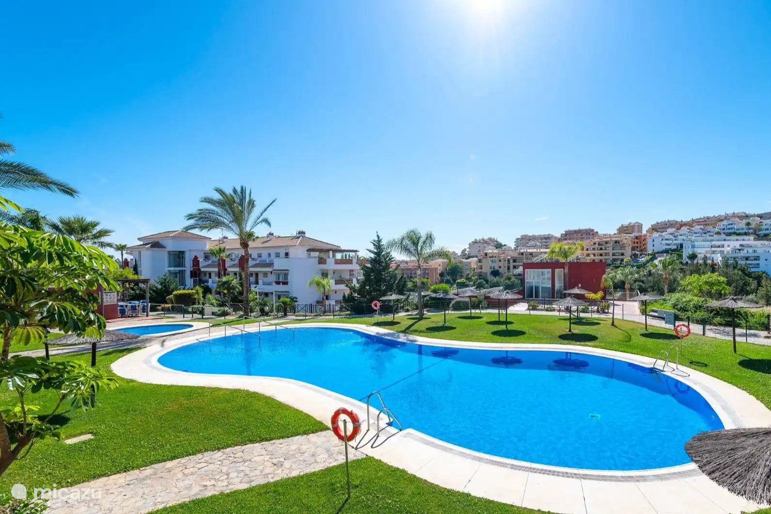 Uitzicht vanaf het grote zwembad. Bij het zwembad is een peuterbad, een toilet en douche ruimte