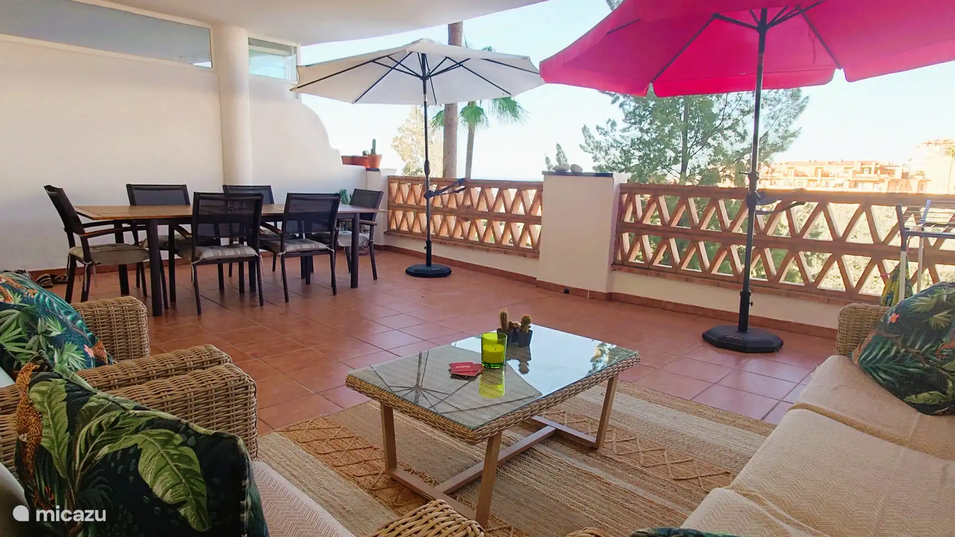 Terras met grote eettafel, lounge set, parasols en prachtig vrij uitzicht op de wijk, de golfbaan en de zee