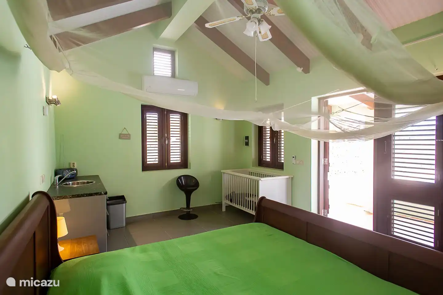 The separate air-conditioned studio contains 2 a large double bed, a storage cupboard, a shower and toilet, a kitchen and seating areas.
