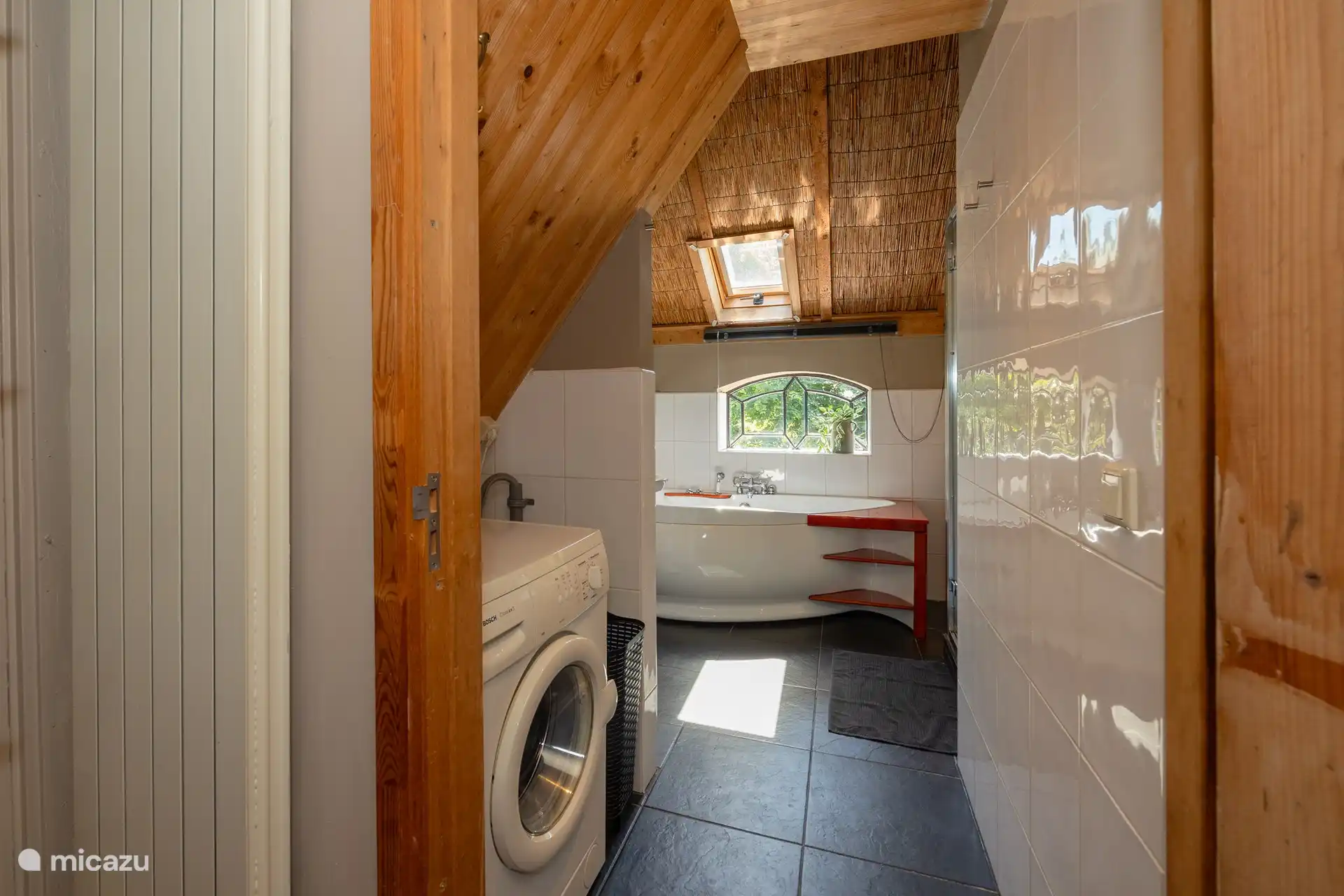 Badezimmer mit Badewanne und Dusche, Waschbecken und Waschmaschine.