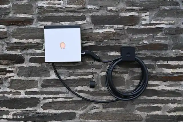 Charging station for electric cars at the facade of the house, near the parking spaces