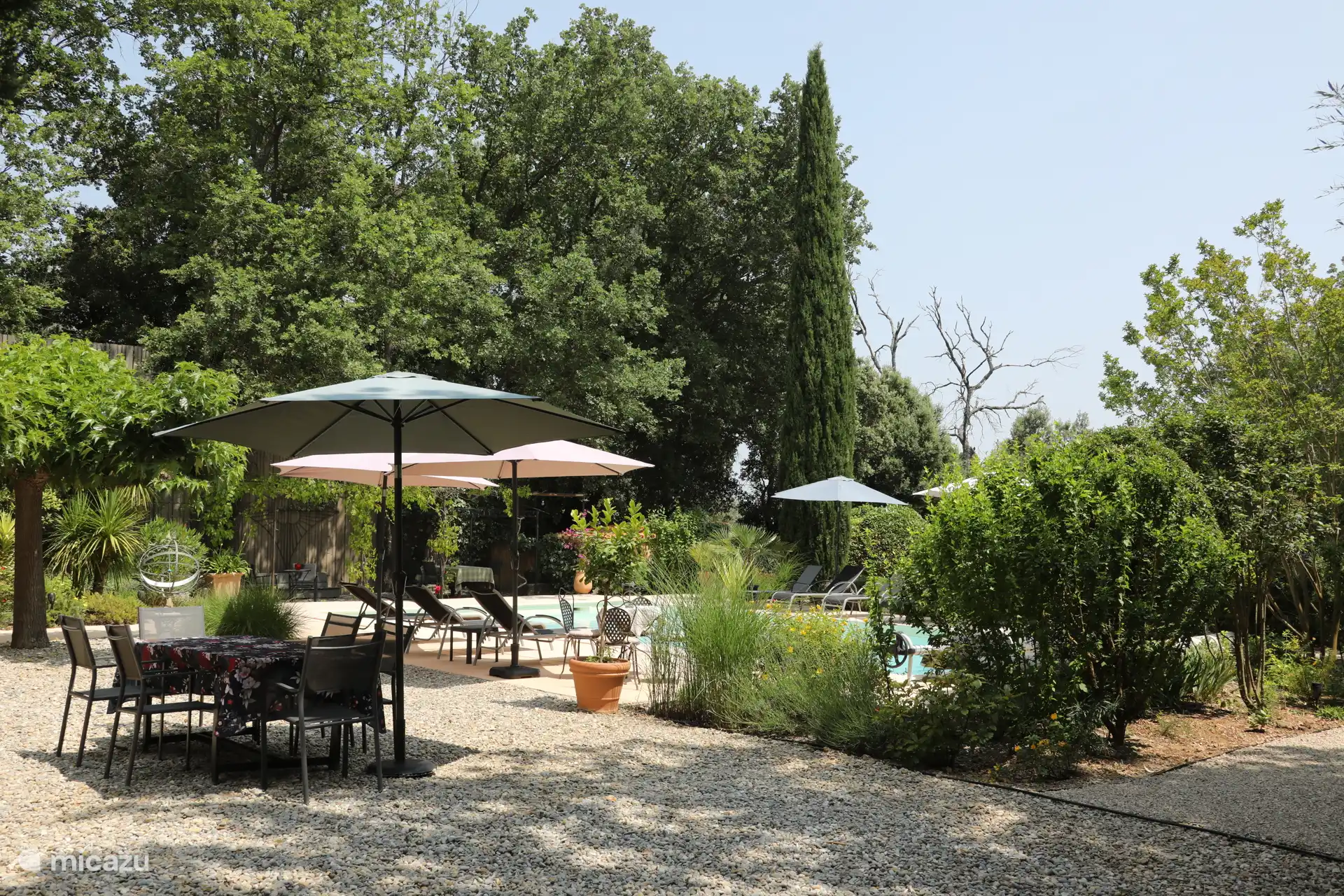 Garten mit Seitenansicht und zusätzlichem Tisch und Stühlen für 8 Personen, Sonnenliege und Sonnenschirme.