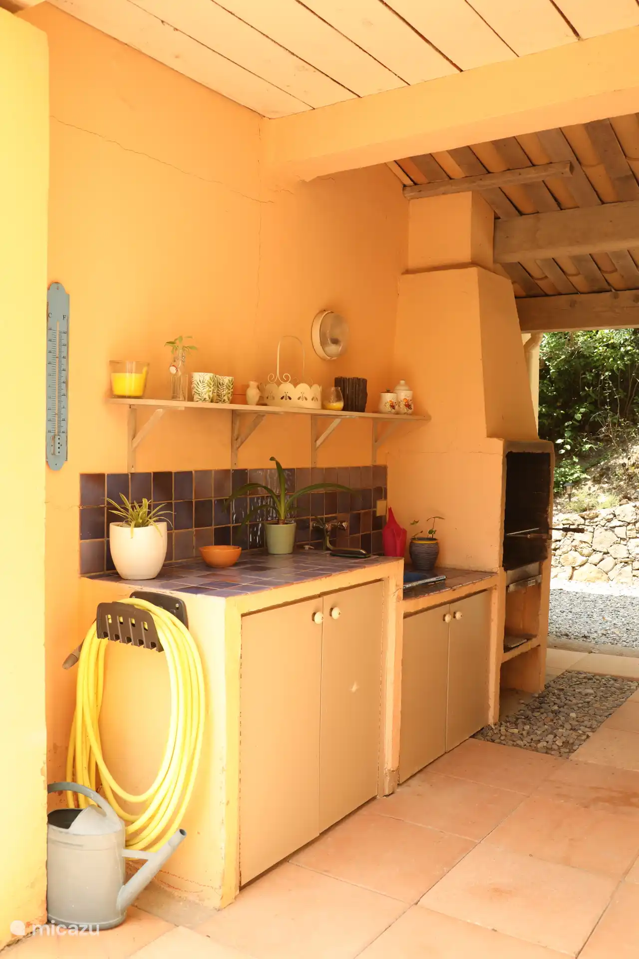 Außenküche mit Grill und Ofen, Wasserhahn und Spüle mit heißem und kaltem Wasser, Durchgang zum Hauswirtschaftsraum mit Laubbläser und Bürsten.