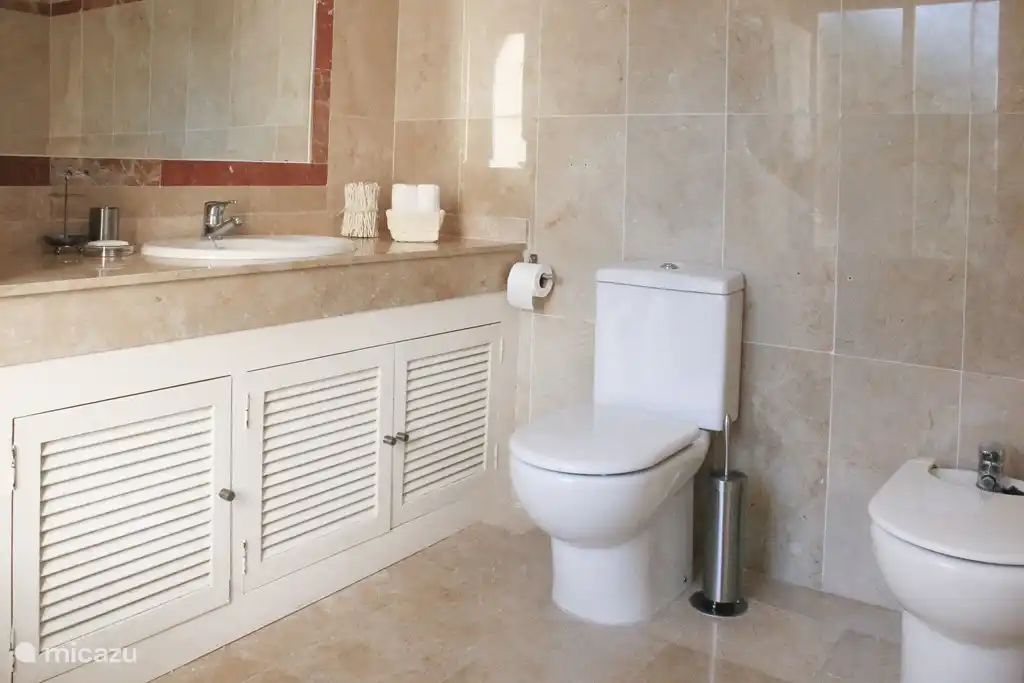 En-suite Badezimmer mit Fenster zum Zimmer mit Balkon. Mit Bad und Dusche mit Glasspritzwand