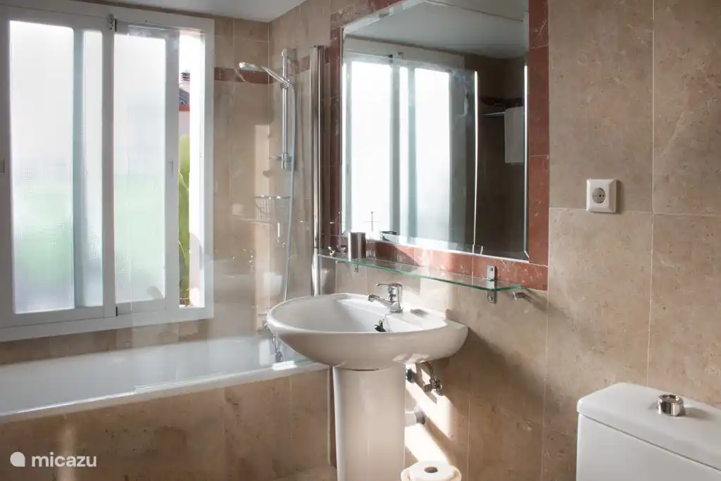 2 Badezimmer mit Badewanne, Dusche mit Glasspritzwand, WC und Waschbecken.