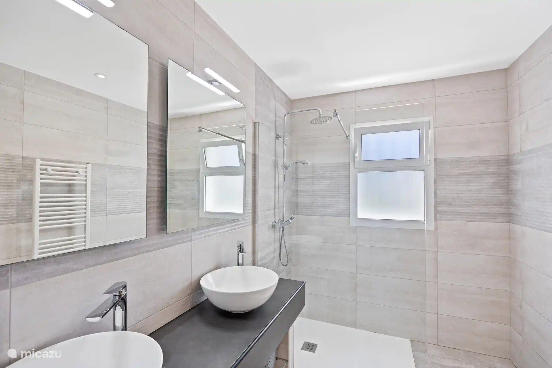 Begin je dag in stijl! Deze moderne badkamer met regendouche, design wastafel en stijlvolle natuurstenen tegels geeft je vakantie meteen een luxe gevoel.