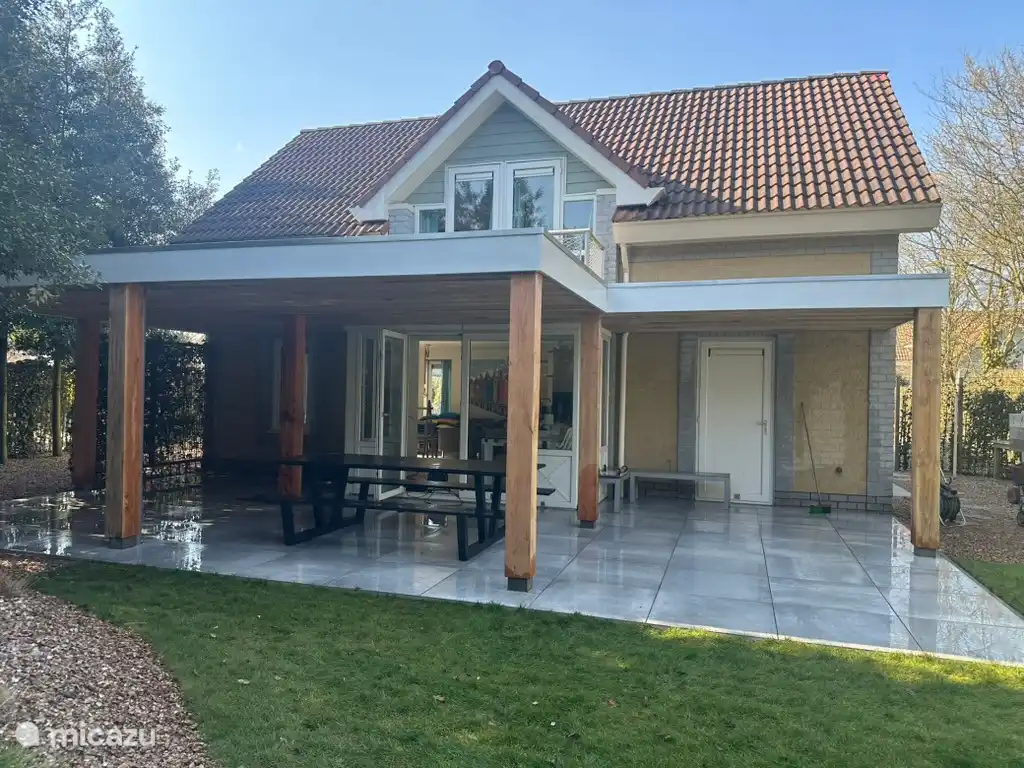 Grote overkapping met loungebanken en buiten eettafel