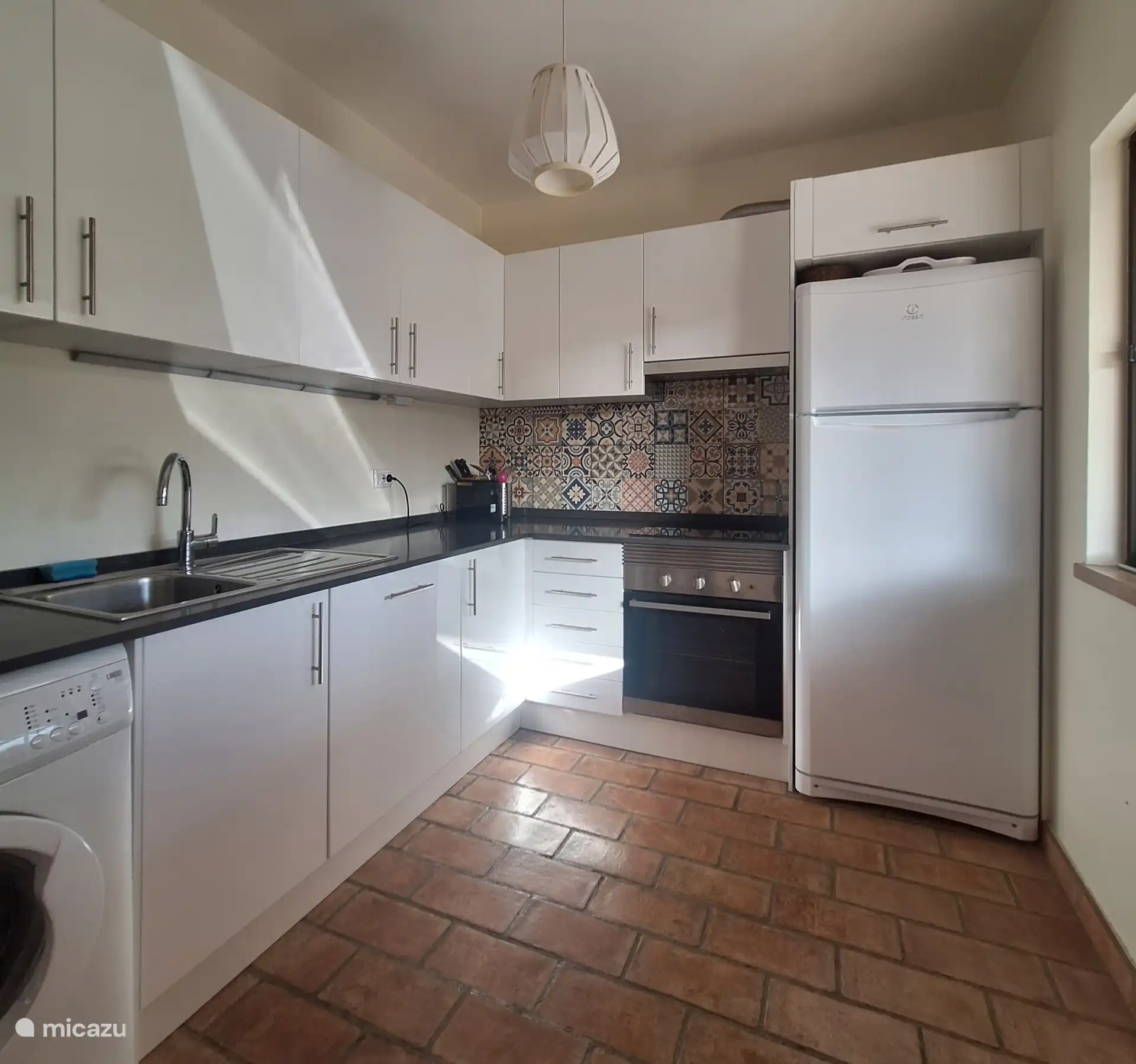 Cocina acogedora con gran nevera, horno empotrado, lavadora y electrodomésticos