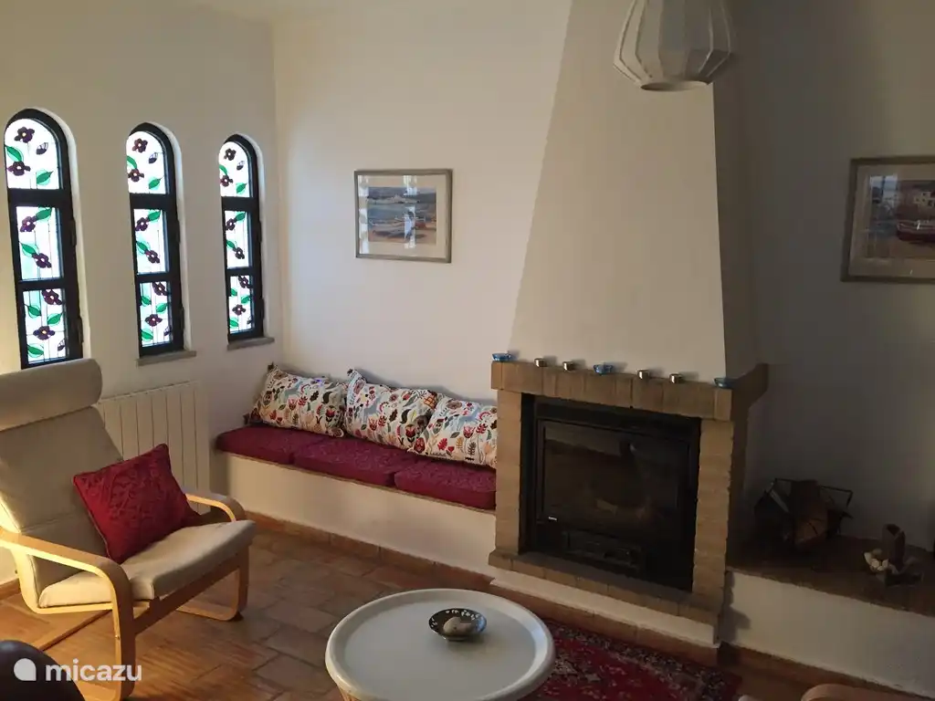 Un acogedor asiento junto a la chimenea en la sala de estar con un televisor inteligente de pantalla grande con Chromecast