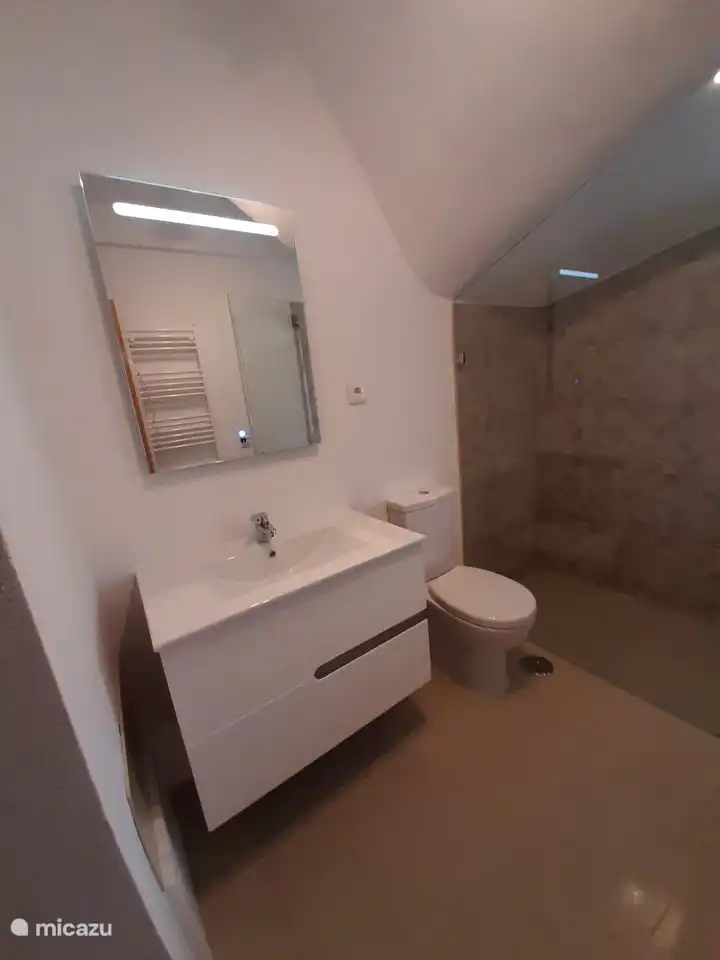 Planta baja: baño moderno con ducha a ras de suelo con radiador toallero y calefacción por suelo radiante